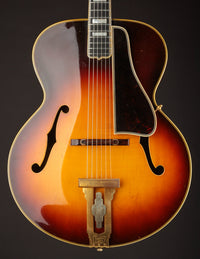 Vintage archtop guitar with a sunburst finish on a black background