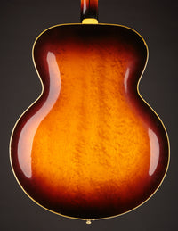 Close-up of a guitar's back with a sunburst finish on a dark background
