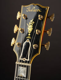 Gibson guitar headstock with brand logo on a dark background