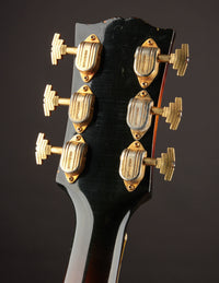 Close-up of a guitar headstock with tuning pegs on a dark background