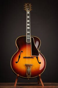 Acoustic guitar on a stand against a dark background