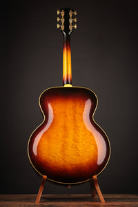 Acoustic guitar with a sunburst finish on a stand against a dark background