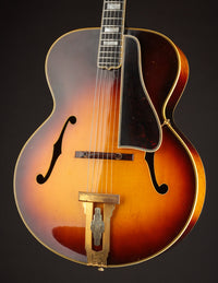 Vintage archtop guitar with a sunburst finish on a black background
