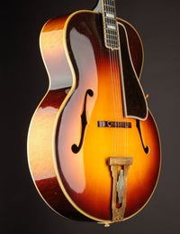 Vintage archtop guitar with a sunburst finish on a black background