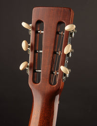 Close-up of a guitar headstock with tuning pegs on a dark background