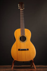 Acoustic guitar on a stand against a dark background