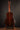 Back view of an acoustic guitar on a stand against a dark background