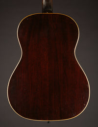 Back view of a 1947 Gibson LG-2 acoustic guitar on a dark background