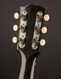 Close-up of a Gibson LG-2 headstock with tuning pegs on a dark background, back view
