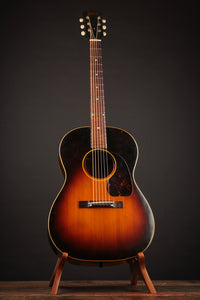 1947 Gibson LG-2 acoustic guitar with a sunburst finish on a stand against a dark background