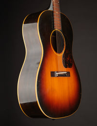 Side view of 1947 Gibson LG-2 acoustic guitar with a sunburst finish on a dark background