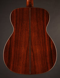 Back view of a wooden acoustic guitar on a dark background