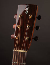 Close-up of a guitar headstock with tuning pegs on a dark background