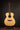 Acoustic guitar on a stand against a dark background