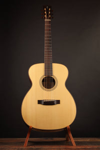 Acoustic guitar on a stand against a dark background
