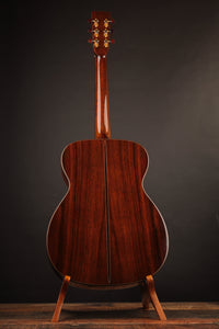 Acoustic guitar on a stand against a dark background