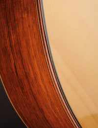 Acoustic guitar with a natural wood finish on a black background, close up 