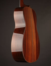 Acoustic guitar with a natural wood finish on a black background, side view
