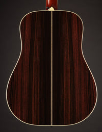 Acoustic guitar with a natural finish on a black background, back view