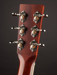 Close-up of a guitar headstock with tuning pegs on a dark background