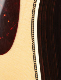 Close up of binding and pickguard on an acoustic guitar 