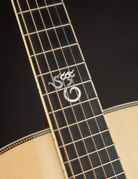 Close-up of a guitar's fretboard with a brand logo on a dark background