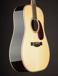 Acoustic guitar with a natural finish on a black background, side view