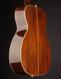Back view of a wooden acoustic guitar on a dark background