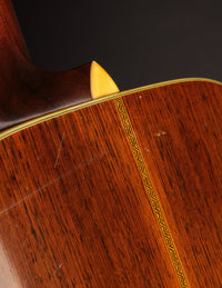 Close-up of a wooden guitar with a decorative inlay on a dark background