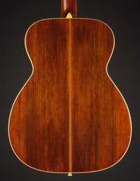 Back view of a wooden acoustic guitar on a dark background