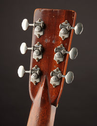 Close-up of a guitar headstock with tuning pegs on a dark background