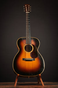 Acoustic guitar on a stand against a dark background