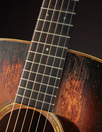 Close-up of a guitar's fretboard and strings with a dark background