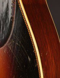 Close-up of a guitar with a dark wood finish and yellow binding.