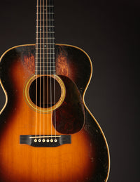 Close-up of an acoustic guitar with a dark brown finish on a black background