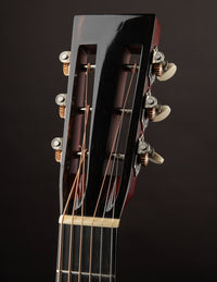 Close-up of a guitar headstock with tuning pegs on a dark background