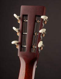 Close-up of a guitar headstock with tuning pegs on a dark background