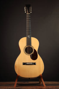 Acoustic guitar on a stand against a dark background
