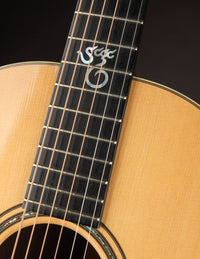 Close-up of a guitar neck with a brand logo on a dark background