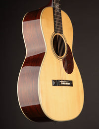 Acoustic guitar with a dark brown back and sides on a black background
