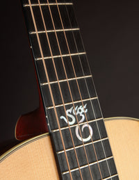 Close-up of a guitar neck with a brand logo on a dark background