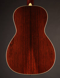 Back view of a wooden acoustic guitar on a dark background