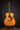 Acoustic guitar on a stand against a dark background