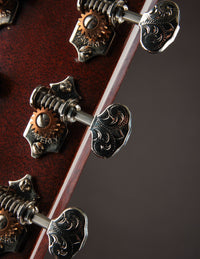 Close-up of a guitar's tuning pegs with intricate designs on a dark background