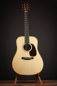 Acoustic guitar on a stand against a black background