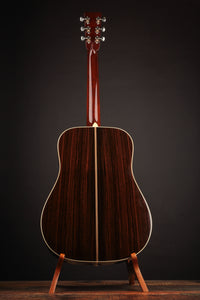 Acoustic guitar on a stand against a dark background