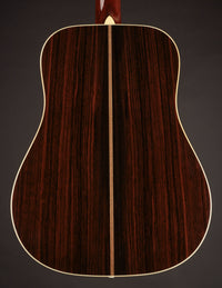 Back view of a wooden acoustic guitar on a dark background