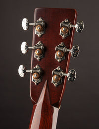 Close-up of a guitar headstock with tuning pegs on a dark background