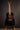 Black acoustic guitar on a stand against a dark background
