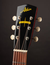 Close-up of a guitar headstock with 'Atkin' branding on a dark background